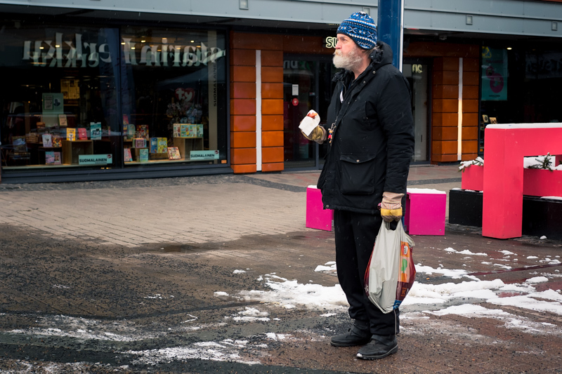 A Finnish man enjoying a hot grilled sausage outdoors on a snowy winter street